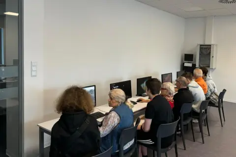 Grupa osób w różnym wieku uczy się obsługi komputera. To idealny przykład, co to zajęcia z samorozwoju dla każdego.