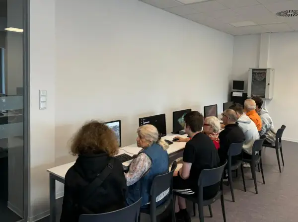 Grupa osób w różnym wieku uczy się obsługi komputera. To idealny przykład, co to zajęcia z samorozwoju dla każdego.